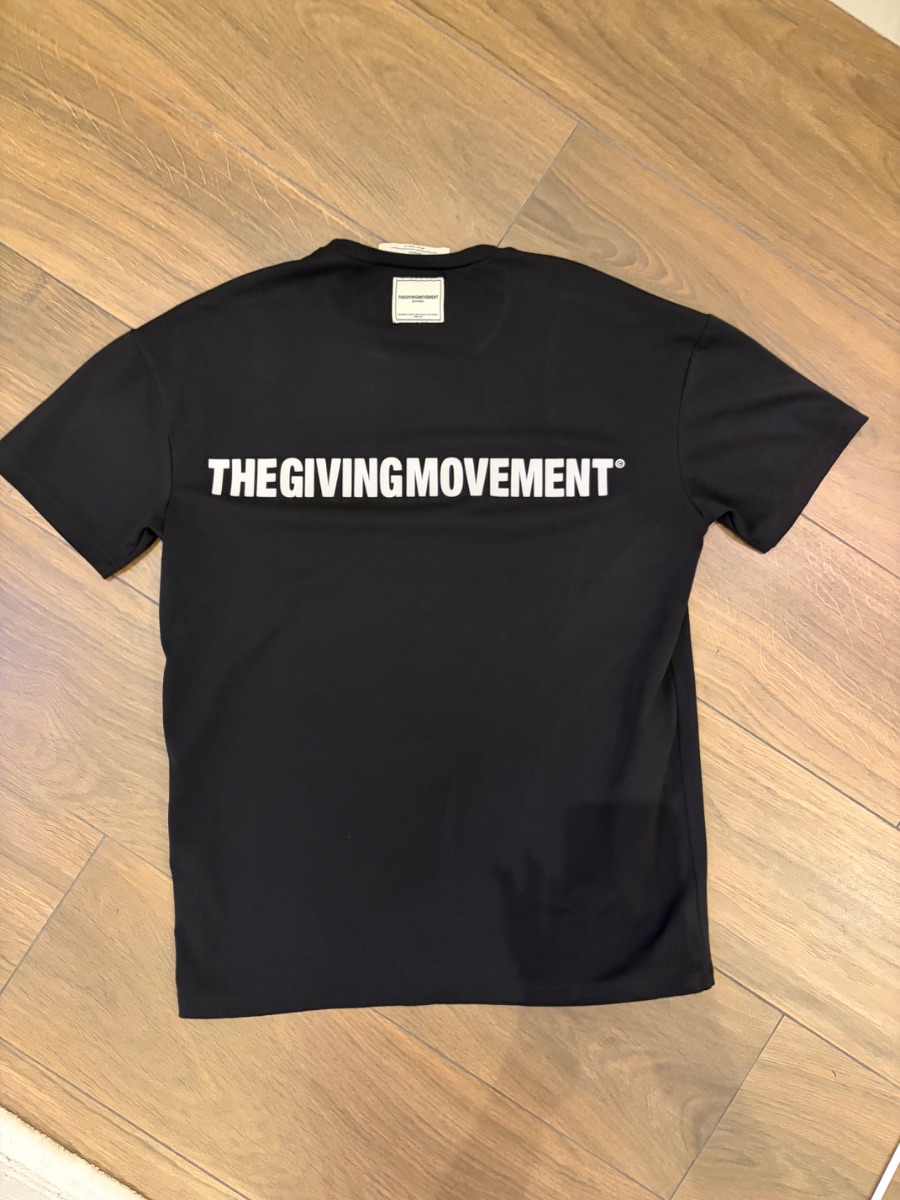The Giving Movement t-shirt with writing on back.