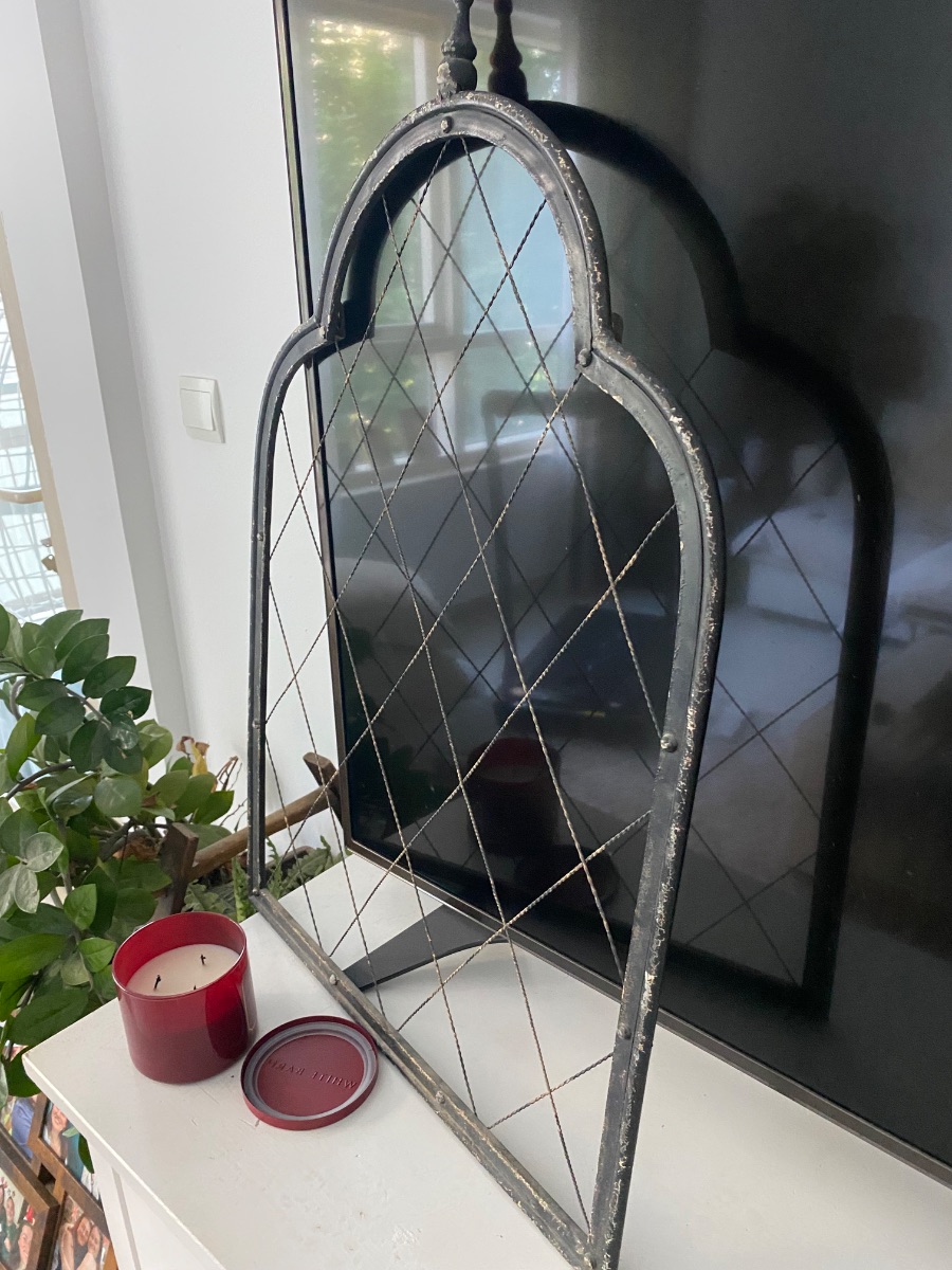 distressed black metal window-pane frame or decorative trellis with a diamond lattice pattern.